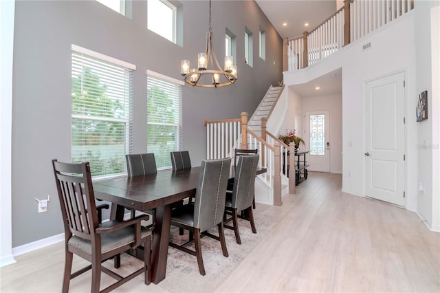 dining room featuring a towering ceiling, an inviting chandelier, and light hardwood / wood-style floors