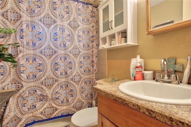 bathroom featuring toilet, vanity, and curtained shower