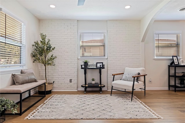 living area featuring light wood-type flooring, plenty of natural light, and brick wall