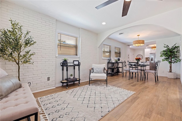 living room featuring light hardwood / wood-style flooring, ceiling fan, and brick wall