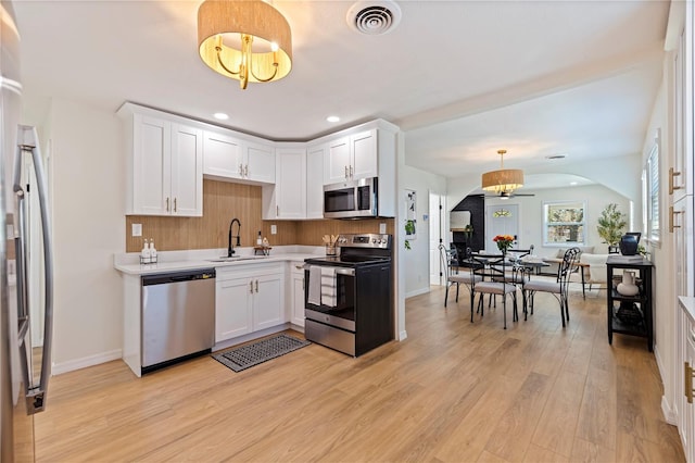 kitchen featuring white cabinetry, appliances with stainless steel finishes, sink, and hanging light fixtures