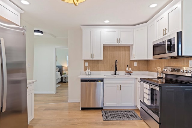 kitchen with white cabinetry, appliances with stainless steel finishes, sink, and light wood-type flooring