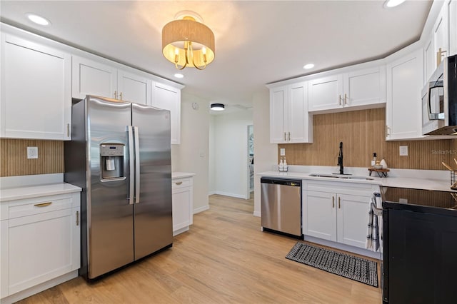 kitchen featuring stainless steel appliances, sink, white cabinets, and light hardwood / wood-style floors