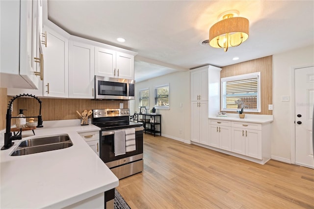 kitchen featuring white cabinetry, appliances with stainless steel finishes, sink, and light wood-type flooring