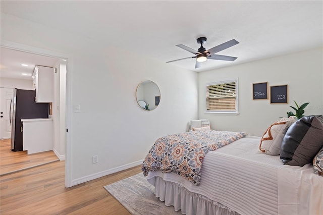 bedroom featuring stainless steel fridge, ceiling fan, and light hardwood / wood-style floors