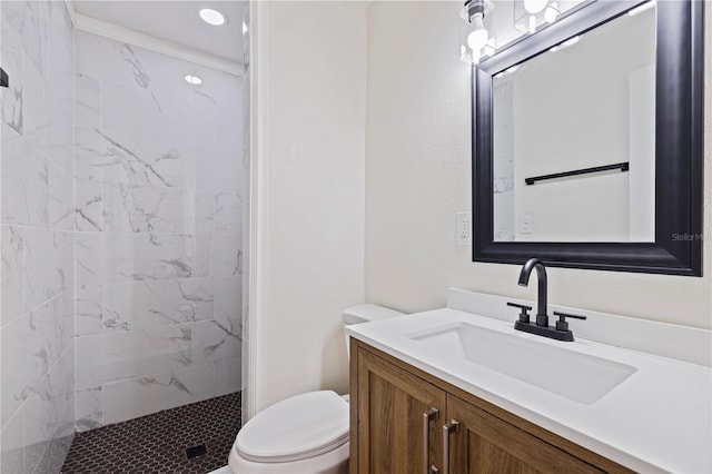 bathroom featuring vanity, a tile shower, and toilet