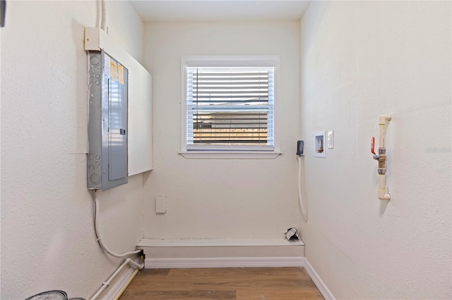 clothes washing area with hardwood / wood-style floors, hookup for a washing machine, and electric panel