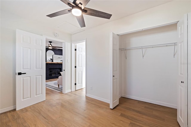 unfurnished bedroom with a closet, a fireplace, ceiling fan, and light hardwood / wood-style floors