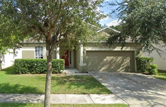 view of property hidden behind natural elements with a front yard and a garage