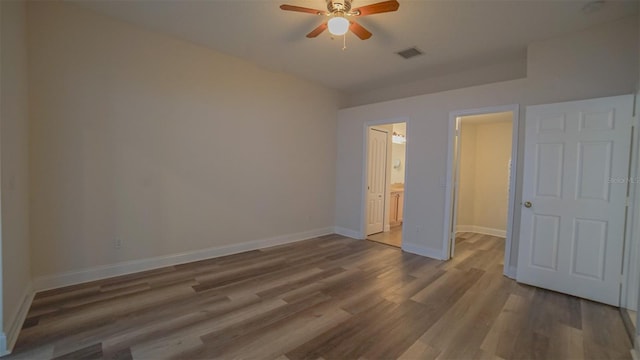 unfurnished bedroom with ceiling fan, connected bathroom, and hardwood / wood-style flooring