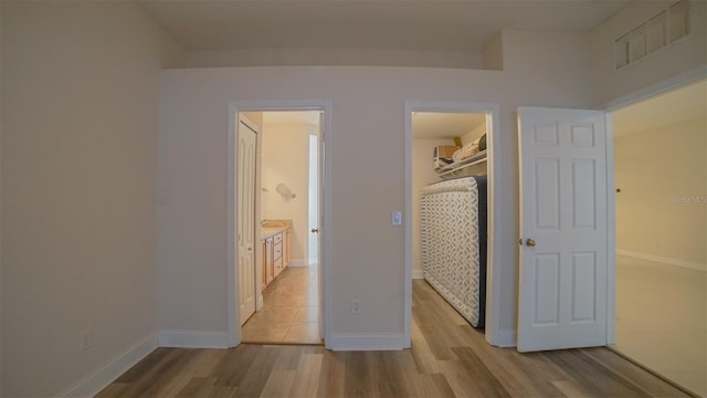 unfurnished bedroom featuring a spacious closet, a closet, and light hardwood / wood-style flooring