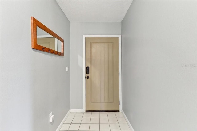 doorway to outside with a textured ceiling and light tile patterned flooring