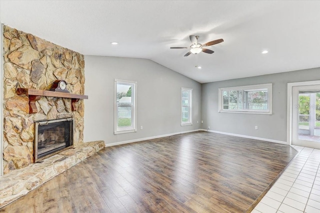 unfurnished living room with ceiling fan, wood-type flooring, lofted ceiling, and a stone fireplace