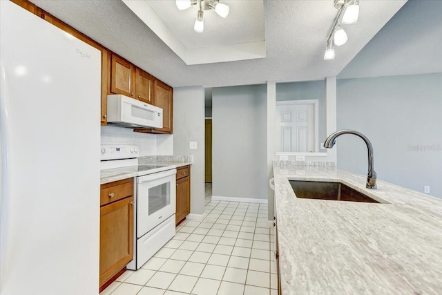 kitchen featuring light tile patterned floors, a tray ceiling, white appliances, a textured ceiling, and sink