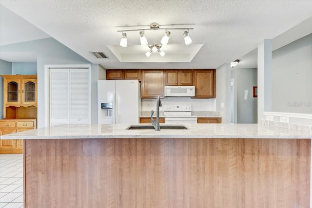 kitchen with white appliances, a raised ceiling, kitchen peninsula, and a textured ceiling