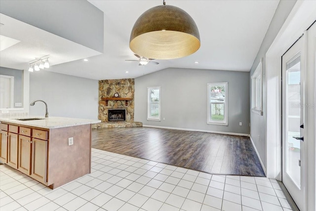 kitchen featuring ceiling fan, lofted ceiling, a fireplace, sink, and light tile patterned floors