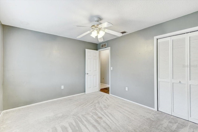 unfurnished bedroom with a textured ceiling, ceiling fan, carpet, and a closet