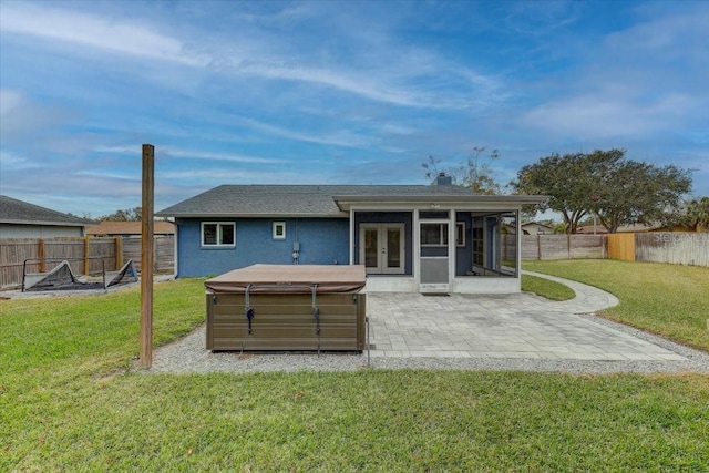 rear view of property with a hot tub, a lawn, a patio area, a sunroom, and french doors