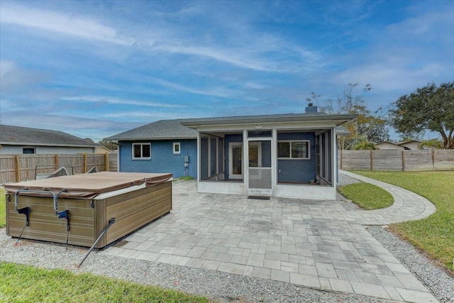 back of property with a hot tub, a patio area, and a sunroom