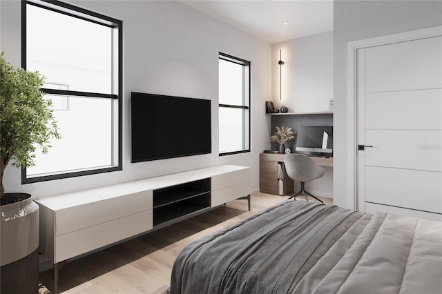 bedroom with built in desk and light hardwood / wood-style flooring