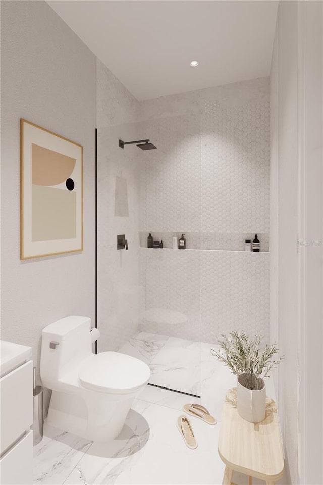 bathroom with a tile shower, vanity, and toilet