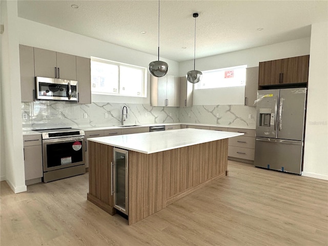 kitchen with stainless steel appliances, a sink, light wood-style flooring, and decorative backsplash