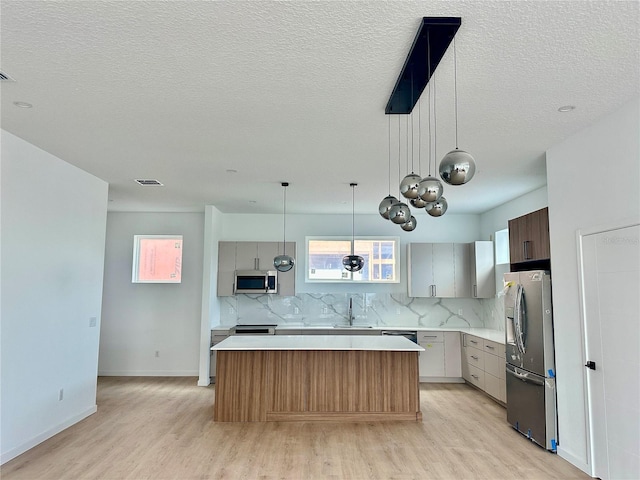 kitchen featuring light countertops, appliances with stainless steel finishes, visible vents, and decorative backsplash