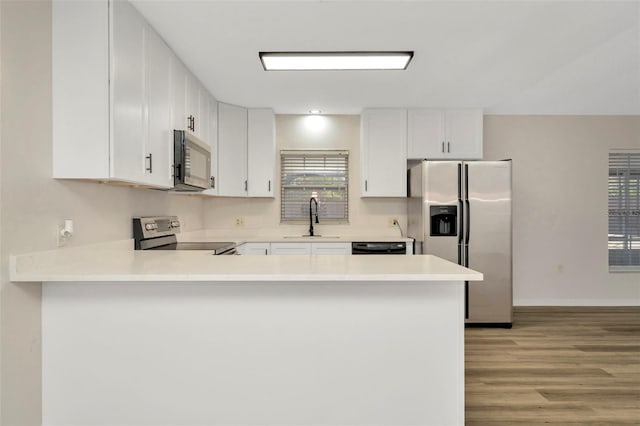 kitchen featuring stainless steel appliances, white cabinetry, sink, and kitchen peninsula