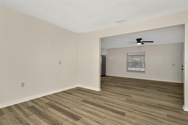 empty room featuring dark wood-type flooring and ceiling fan