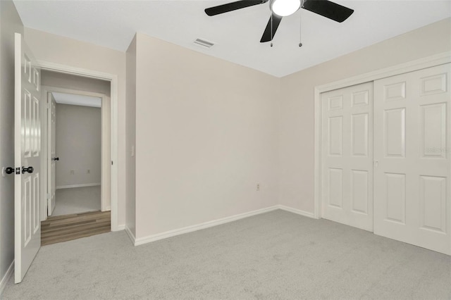 unfurnished bedroom with ceiling fan, light carpet, and a closet