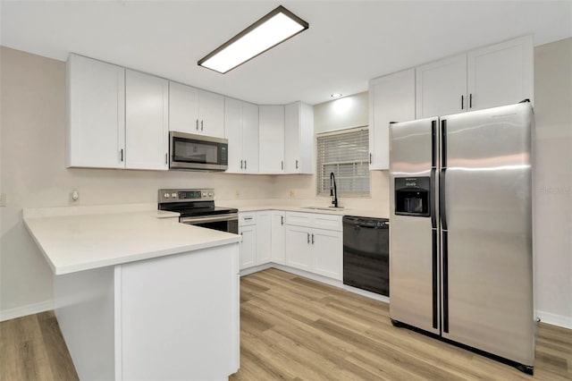 kitchen featuring sink, light hardwood / wood-style flooring, appliances with stainless steel finishes, kitchen peninsula, and white cabinets