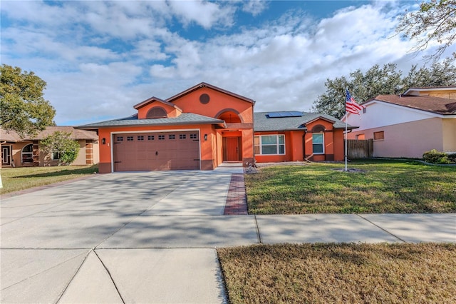 view of front facade featuring a front lawn, a garage, and solar panels