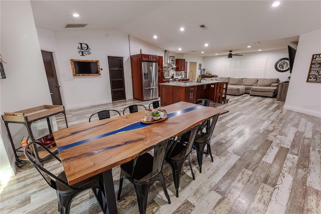 dining space featuring vaulted ceiling, sink, ceiling fan, and light wood-type flooring