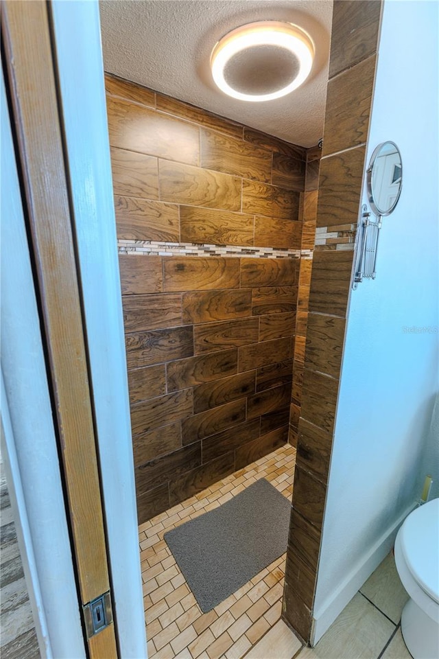 bathroom with tile patterned flooring, toilet, and a textured ceiling