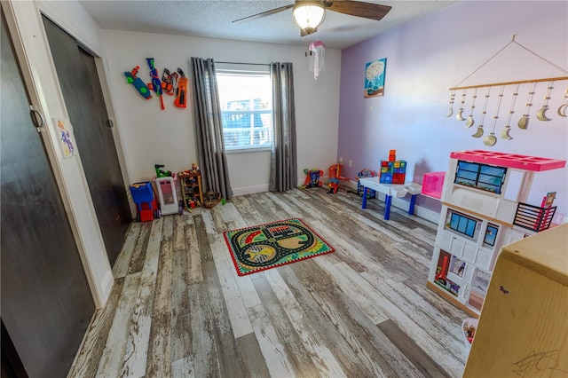 recreation room with hardwood / wood-style flooring, ceiling fan, and a textured ceiling