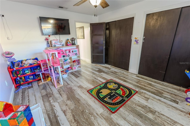 recreation room with light hardwood / wood-style floors and ceiling fan