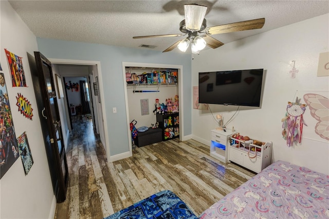 bedroom featuring ceiling fan, hardwood / wood-style floors, a textured ceiling, and a closet