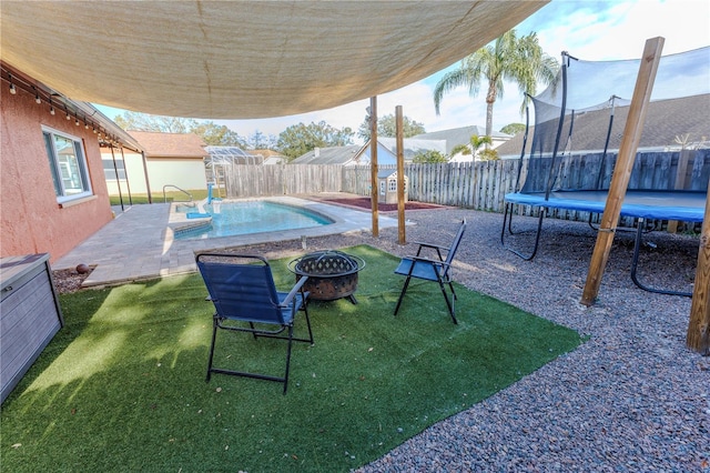 exterior space with a fenced in pool, a trampoline, and a fire pit