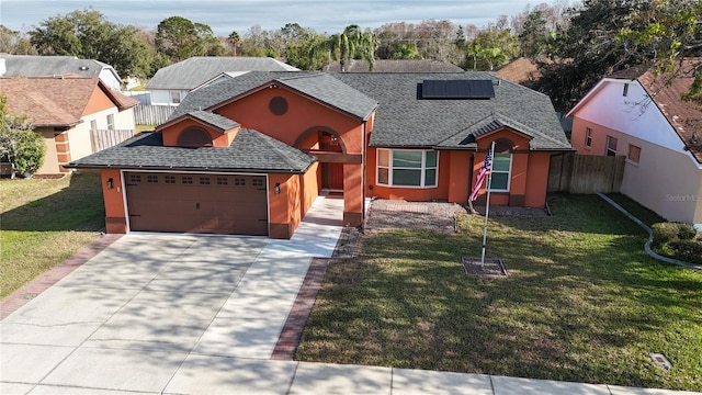 view of front of home featuring a garage, a front lawn, and solar panels