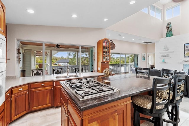 kitchen featuring lofted ceiling, a kitchen island, a breakfast bar, sink, and stainless steel gas cooktop