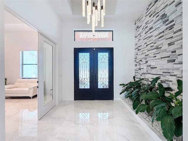 foyer entrance with french doors, a high ceiling, and a chandelier