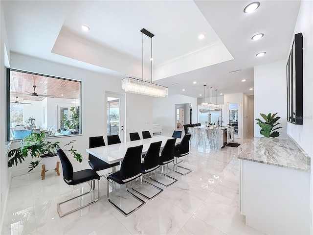 dining space featuring ceiling fan, ornamental molding, a tray ceiling, and sink