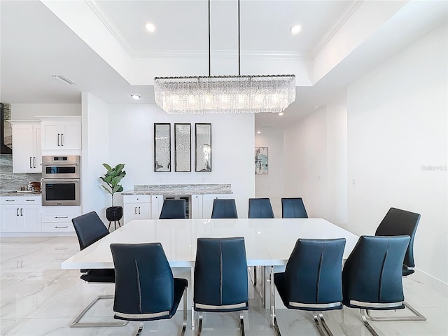 dining area featuring crown molding, a tray ceiling, and a notable chandelier