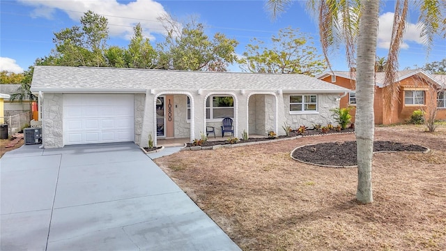 ranch-style home with a garage, central AC unit, and covered porch