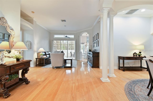 interior space with light wood-type flooring, ornate columns, and ornamental molding