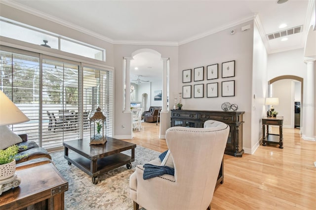 living room featuring light wood-type flooring, ornate columns, ornamental molding, and ceiling fan