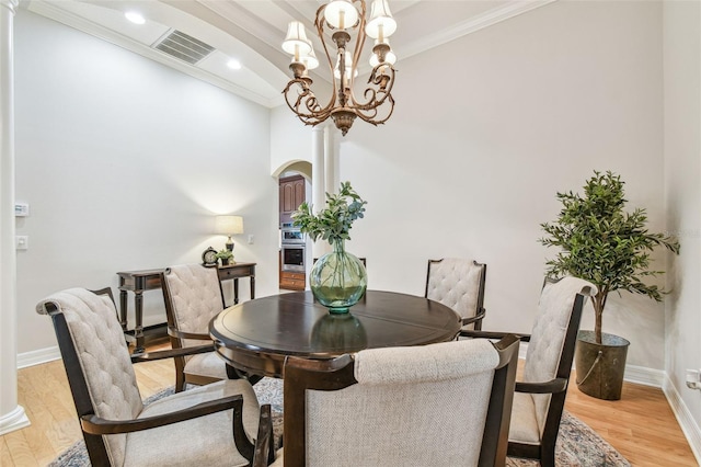 dining room featuring crown molding, an inviting chandelier, and light hardwood / wood-style flooring