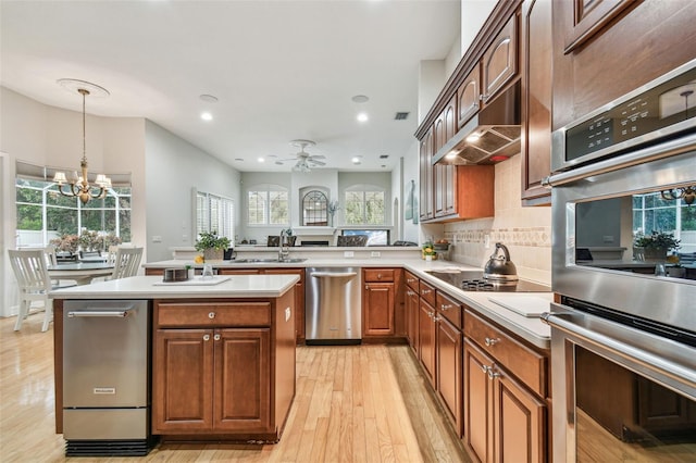 kitchen featuring appliances with stainless steel finishes, tasteful backsplash, a center island, ceiling fan with notable chandelier, and sink