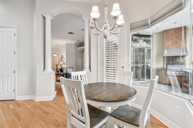 dining area with light hardwood / wood-style flooring, crown molding, a chandelier, and decorative columns