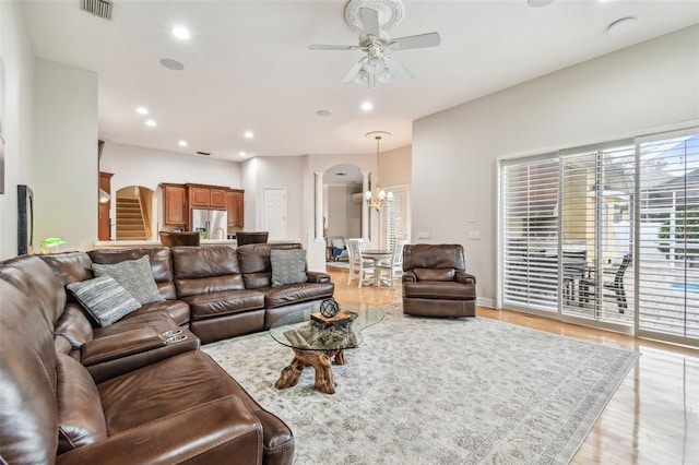 living room featuring ceiling fan with notable chandelier and light hardwood / wood-style flooring